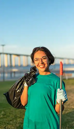 Volunteer cleaning litter from the ground in a public area, helping create a cleaner, safer environment as part of a community service effort by Warm Hearts Donate.